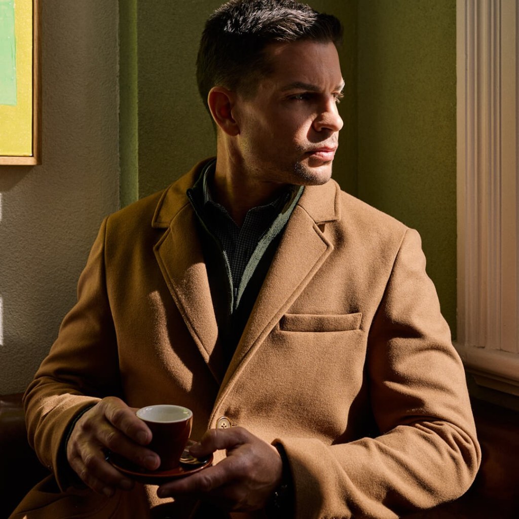 Man in coat and jumper for retail brand positioning campaign.